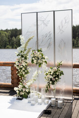 Vertical photo of wedding ceremony with white transparent screens and fresh flowers and candles. Wedding exit ceremony with two screens with feather and white rose