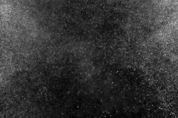 Abstract splashes of water on black background. Freeze motion of white particles. Rain, snow overlay texture.