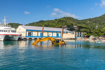 Fototapeta na wymiar Dredging, pontoon excavator sunk in harbor in Carriacou, Grenada