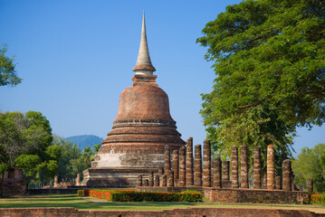 Fototapeta premium Buddhist stupa on the ruins of ancient temple in the historical park of Sukhothai on a sunny day. Thailand