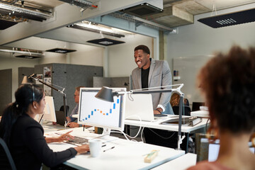 Smiling businessman discussing with young businesswoman over graph at office