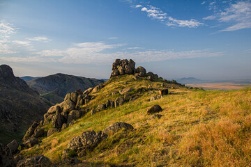 Mountain peak with rocks and high grass landscape with under blue sky in the Macin mountains, Dobrogea, RomaniaMacin Mountains, Dobrogea, Romania