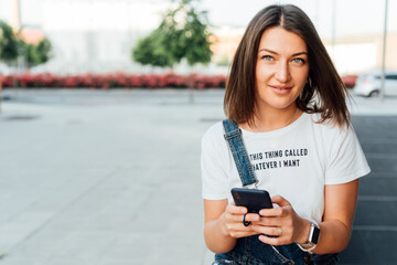 Portrait of young girl with green eyes looking at camera with cell phone in hand.