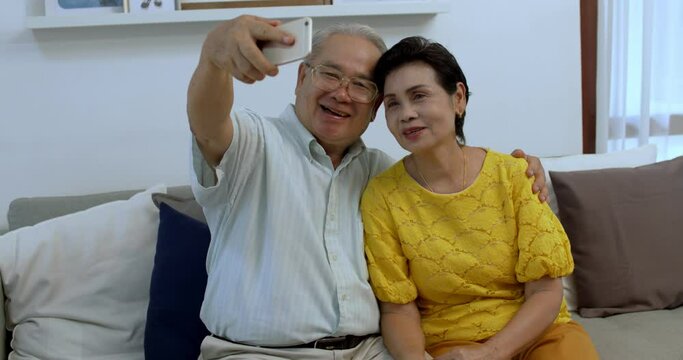 couple sit on sofa at home make self-portrait picture on smartphone, contemporary senior husband and wife technology users have fun taking selfie on cellphone in living room