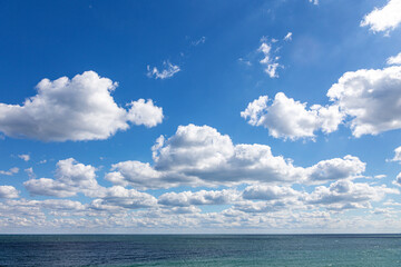 Blue sky with white clouds over the endless sea on a summer sunny day. Picturesque seascape.