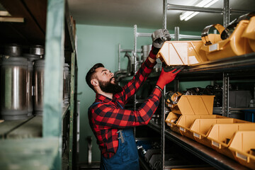 Fototapeta na wymiar Handsome adult man working in car and truck spare parts warehouse.