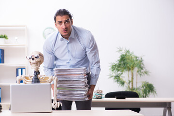 Young male employee and skeleton in the office