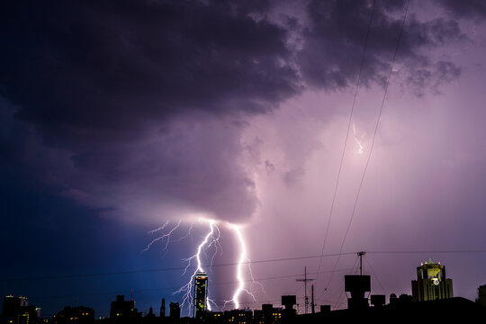 Photo of beautiful powerful lightning over big city, zipper and thunderstorm, abstract background, dark blue sky with bright electrical flash, thunder and thunderbolt.