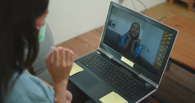 Portrait of young Asian Thai woman chat on laptop, VDO conference on sofa as working at home during corona virus or Covid 19