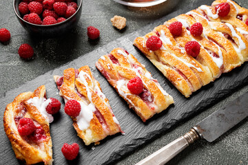 Braided raspberry danish pastry with glaze and fresh berries.