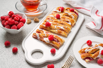 Braided raspberry danish pastry with glaze and fresh berries.