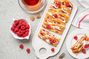 Braided raspberry danish pastry with glaze and fresh berries.