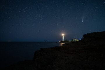 HDR Landscape view on famous Neowise comet over white Lighthouse at night