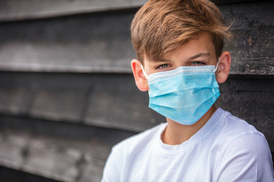 Boy teenager teen male child wearing face mask outside in the Coronavirus COVID-19 pandemic
