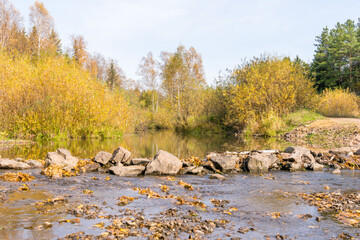A small stream on backdrop of autumn forests 