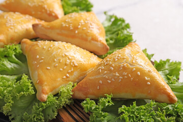 Delicious samsa with lettuce leaves on kitchen board, close-up