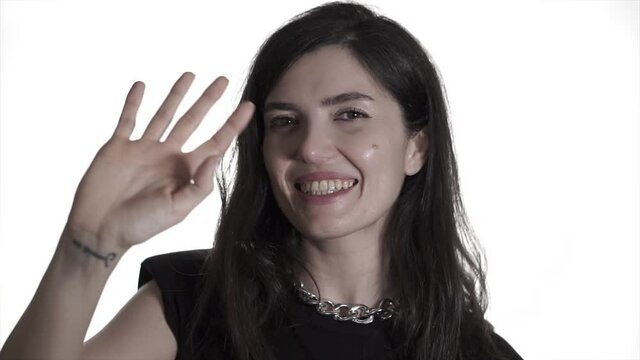 Young woman is saying hi, hello with her hand gestures. Hand wave, beauty female in studio face shot