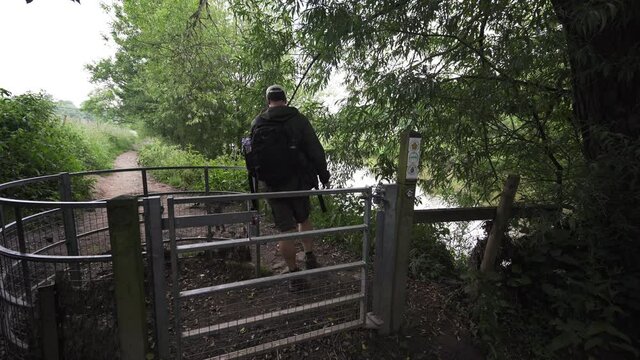 A man walking through a metal gate in the countryside