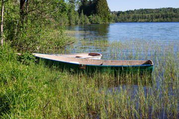 Wooden fishing boats at the shore of a forest lake, standing in the grass...