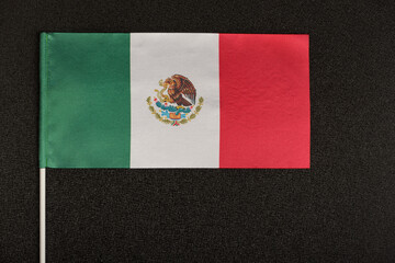 Table flag of Mexico on black background. Striped tricolor green white red