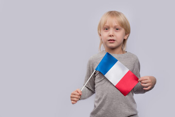 Fair-haired boy holding flag of France. Training in France. Learning French for children