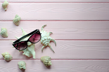 Fototapeta na wymiar Sea shells, sunglasses on a pink wooden background. Summer, vacation and Travel concept. Minimal. Copy space, flat lay.