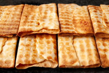 A close-up of hot crispy cookies stacked in a row on black marble. Freshly baked cookies.