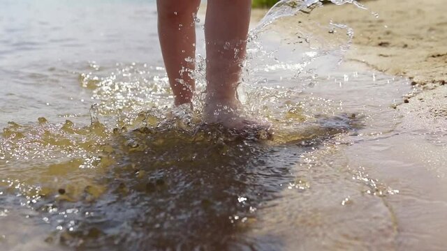 Close-up of a little girl's feet walking on a sandy beach water.