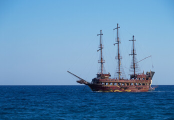 The painted brown ship made like an ancient sailing ship swimming in the sea. Copy space. Horizontal orientation.