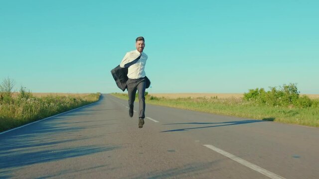 Close up businessman runs removes the jacket country road near a wheat field freedom concept outdoors handsome winner jumping elegant slow motion