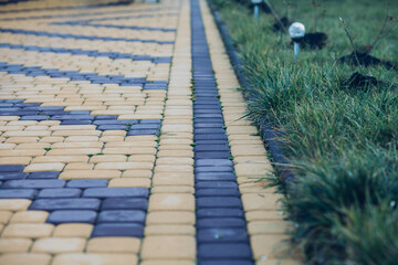 Nested pavers of various colors, around the grass is green, chic garden