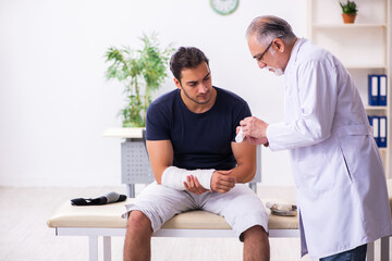 Obraz premium Young injured man visiting experienced male doctor traumatologis