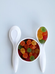 Sweet mixed color jelly candy in a white spoon against white background with copy space