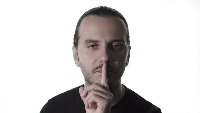 An young handsome man is shushing, mute point or stop with his gestures. Ssh concept, calm and relax.