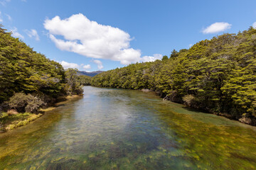 Fototapeta na wymiar Mavora River at the point it drains out of the South Mavora Lake with forests lining each side.