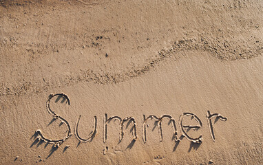 The word SUMMER is written in the sand. The concept of tourism, beach and sea or ocean recreation.