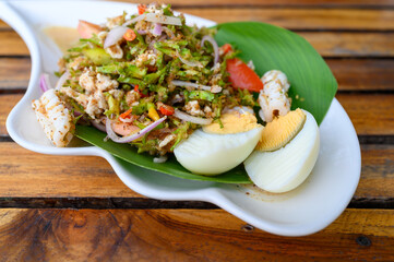 Wing Bean Sea food Salad with boiled eggs on wooden table, Thai food