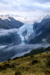 Franz Josef Glacier with wispy clouds in front of it it. After sunset, at dusk, from the view of the summit of Alex Knob. Franz Josef Glacier, South Island, New Zealand.