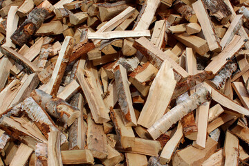 Dry chopped pile of firewood from logs. Preparation of firewood for the winter. Stacks of firewood. Wooden background.
