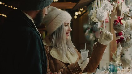 Young couple buys gifts in Christmas fair. Happy couple shopping together. Merry Christmas and Happy New Year! - Powered by Adobe