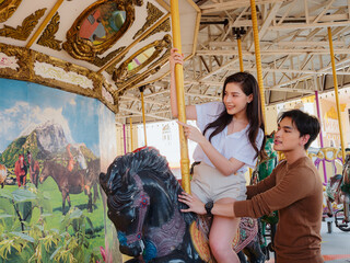 Fototapeta na wymiar Young Asian couple having fun at an amusement park ride. Enjoyment in amusement park Concept.