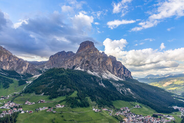 View of the alpine villages of Colfosco and Corvara at the foot of the mountain Sassongher. Italian...