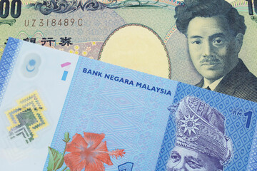 A macro image of a Japanese thousand yen note paired up with a blue, plastic one ringgit bank note from Malaysia.  Shot close up in macro.