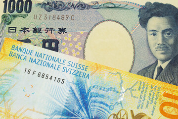 A macro image of a Japanese thousand yen note paired up with a yellow Swiss ten franc bill.  Shot close up in macro.