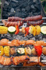 Variety of meat, fish and vegetable ingredients put on metal skewers and placed over charcoal grill.
