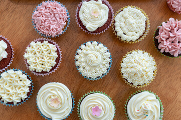 Home baked cupcakes beautifully decorated with buttercream on top placed on wooden table.