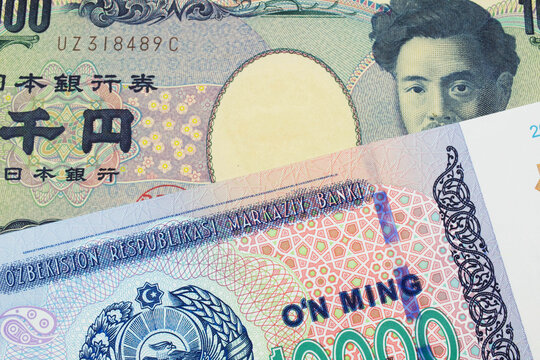 A macro image of a Japanese thousand yen note paired up with a blue, white and green ten thousand som note from Uzbekistan.  Shot close up in macro.