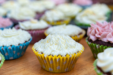 Home baked cupcakes beautifully decorated with buttercream on top placed on wooden table.