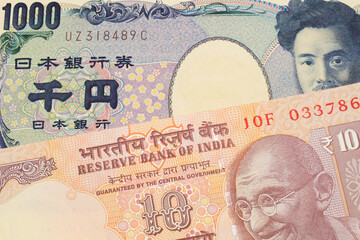 A macro image of a Japanese thousand yen note paired up with a orange ten rupee bill from India.  Shot close up in macro.