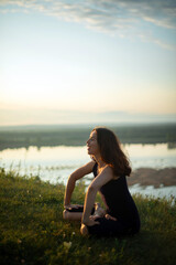 Fototapeta na wymiar Yoga practice and meditation in nature in sunrise. Woman practicing near big river Kama.